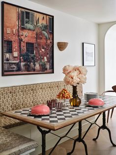 a dining room table with plates and vases on it in front of a painting