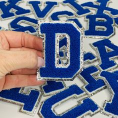 someone is making letters out of blue and silver sequins that spell out the letter d