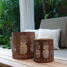 two pineapple candle holders sitting on top of a wooden table next to a couch