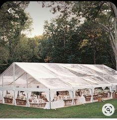 a large tent set up in the middle of a field with tables and chairs under it