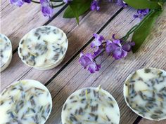 several cupcakes with purple flowers in the middle on a wooden table next to them