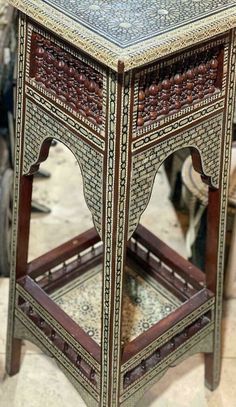 an ornate wooden table with intricate carvings on the top and bottom, sitting on a tile floor