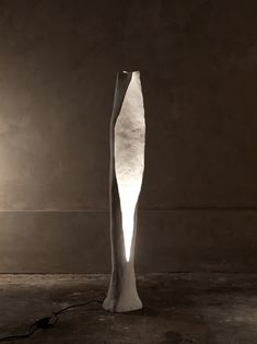 a large white sculpture sitting on top of a floor next to a light that is turned on