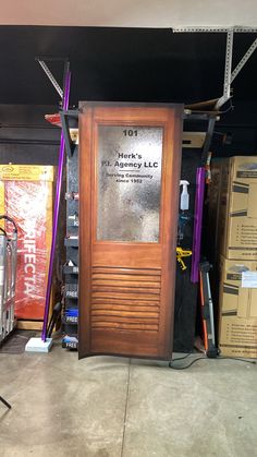 a large wooden door sitting inside of a garage next to boxes and other items on the floor