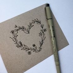 a pen is laying on top of a piece of paper with a heart drawn on it