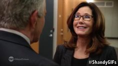 a woman with glasses talking to a man in a suit