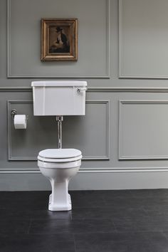 a white toilet sitting in a bathroom next to a wall with gray paneled walls