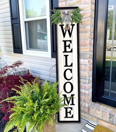 a welcome sign on the front door of a house with potted plants next to it