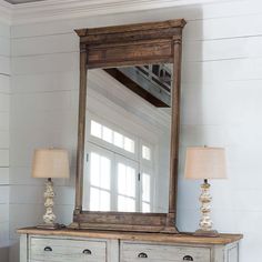 an old dresser with a mirror on top of it and two lamps next to it