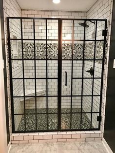 an open glass shower door in a bathroom with white tile and black trim on the walls