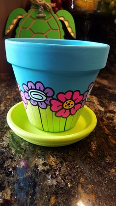 a blue flower pot sitting on top of a green saucer next to a yellow plate