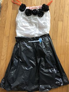 a black and white dress with flowers on the top is laying on a wooden floor