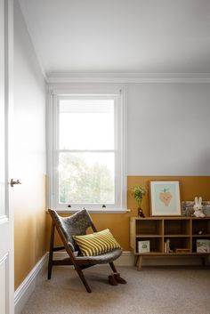 a chair sitting in front of a window next to a book shelf