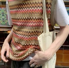 a man wearing a knitted vest and holding a bag