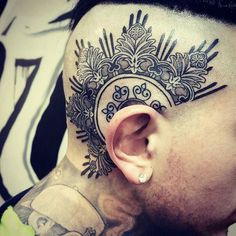 a man with a tattoo on his neck and behind the ear has an intricate design