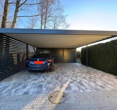 a car is parked in the driveway next to a garage with an attached carport