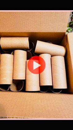 an open cardboard box filled with rolls of toilet paper and a video player in the background