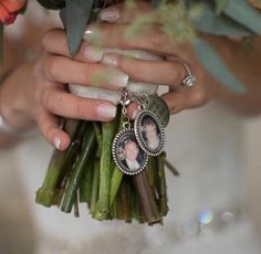 a bride holding her bouquet with an oval photo charm hanging from it's center