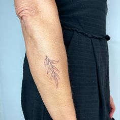 a woman's arm with a tattoo on it that has a leaf design on it