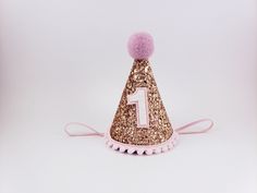 a pink and gold party hat with a number one on it's side,