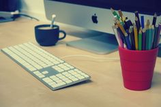 a cup filled with pencils sitting next to a keyboard and mouse on top of a desk