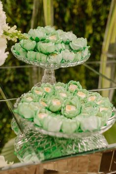 three tiered trays filled with green and white cupcakes on top of a glass table