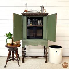 a green cabinet sitting on top of a table next to a potted plant