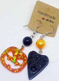 three different shaped earrings are displayed on a white surface with a tag attached to it