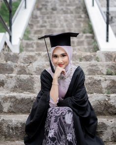 a woman in a graduation gown sitting on some steps with her hand under her chin