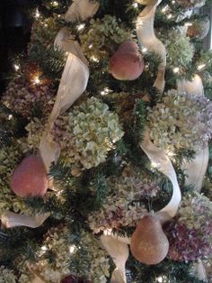 a decorated christmas tree with white ribbons and pomegranates