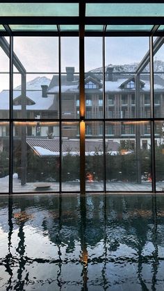 an indoor swimming pool in front of large windows with snow on the mountains behind it