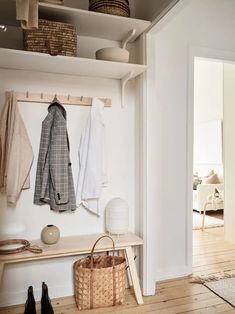 an entryway with white walls and wooden flooring, coat rack on the wall