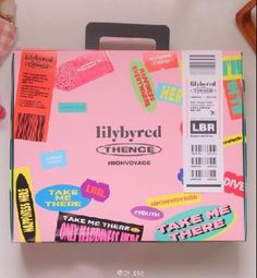 a pink box with stickers on it sitting next to a pair of scissors and other items