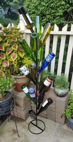 a tall glass vase sitting on top of a metal stand in front of a white fence