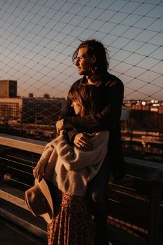 a man and woman standing next to each other on a bridge