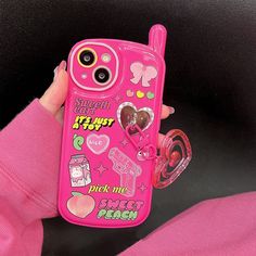 a person holding a pink cell phone with stickers on it's back cover