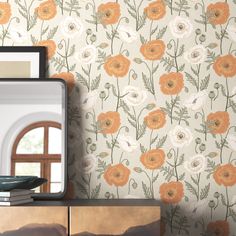 an orange and white flowered wallpaper next to a dresser with a mirror on it