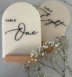 there are two table signs that say one and the other is in black ink on white paper