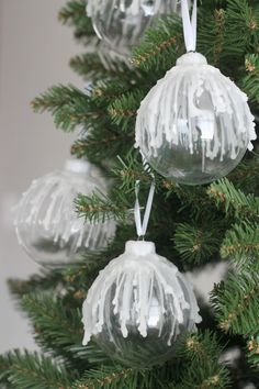 three glass ornaments hanging from the top of a christmas tree with white icing on them