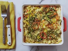 a casserole dish with noodles and vegetables in it next to a yellow napkin