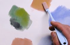 someone using a paint brush to paint different colors