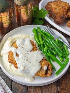 a plate with chicken, mashed potatoes and green beans