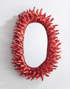 a mirror that is on the wall with some red decorations around it and a white background