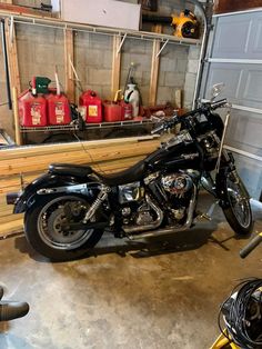 a black motorcycle parked in a garage next to some red gas can'tisters