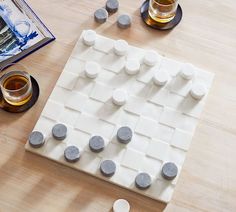 a board game made out of rocks on a wooden table next to two cups of tea