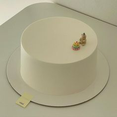 there is a white cake with two small bears on the top and one has a yellow tag