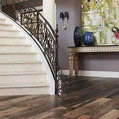 a staircase in a house with wooden floors and paintings on the wall behind it,