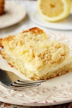 a piece of cake on a plate with a fork next to it and lemons in the background