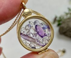 "This 14K yellow gold locket has been filled with hand selected natural amethyst crystals + faceted  gems, and accented by natural sparkling AAA+ grade Herkimer Diamond quartz crystals. These are genuine and naturally occurring high grade gemstones from locations around the world, not beads or glass or synthetic stones.  You will receive this exact locket and stone selection. This high quality floating locket is US made with 14K gold and glass and can come on a 14K gold chain, if you wish. The 16\" chain option is pictured. The longer lengths are slightly thicker. This is a floating or shaker locket (meaning the crystals move around freely) with a magnetic closure that opens from the top to easily access these miniature beauties. Or even add your own micro treasures.   These are so magical Faceted Gold Amethyst Gemstones, Gold Round Amethyst Gemstones, Gold Amethyst Birthstone Gemstones, Gold Amethyst Gemstones For Healing, Glass Locket Pendant, Amethyst Crystals, Glass Locket, Natural Jewelry, Floating Lockets