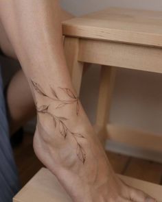 a woman's foot with a tattoo on the side of her leg and a table in the background